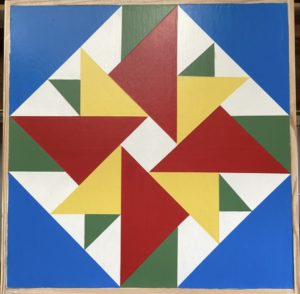 Red, green, yellow, & blue aster pattern barn quilt hand painted on wooden sign board